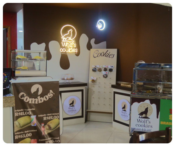 Fachada da Wolf's Cookies & Fit, letreiro do lobo em neon e vitrine de cookies